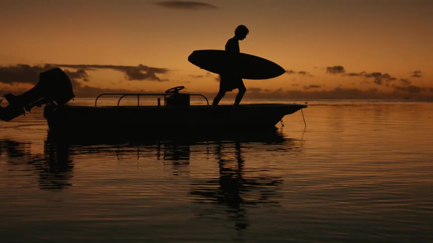 A man walks on his boat with a surfboard