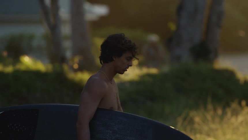 A man carries his surfboards towards the shore