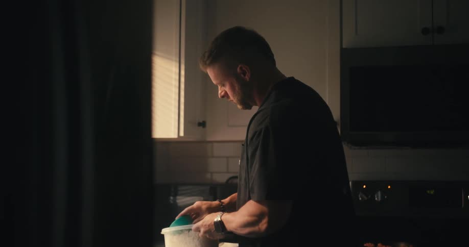 Man standing in kitchen near the window scoops out rice