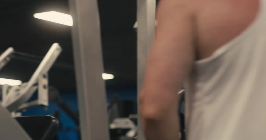 A man moving weights from one bar to another in a gym
