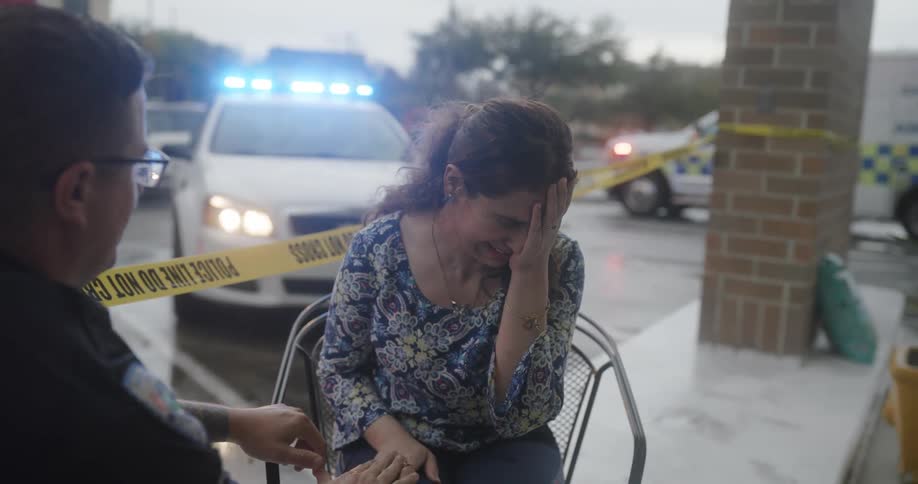 A crying woman sitting on a bench talking to a police officer
