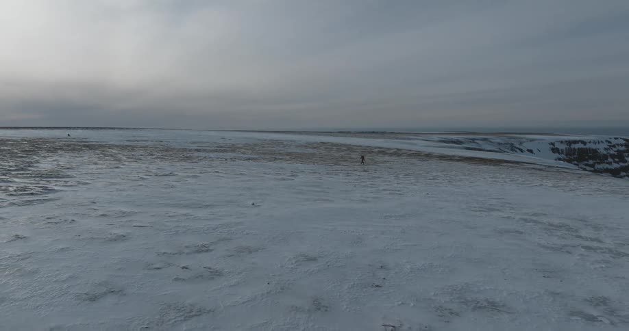 A man walking on a large flat glacier