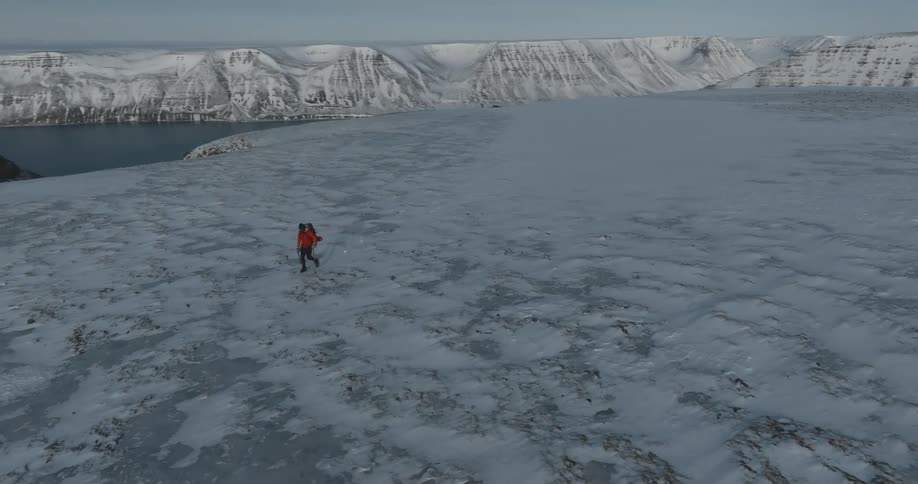 Solitary man hikes on the frozen arctic mountains at evening