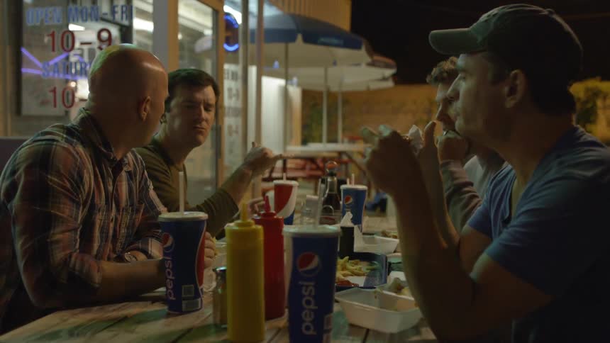 Four men eating their dinner outdoors at a restaurant