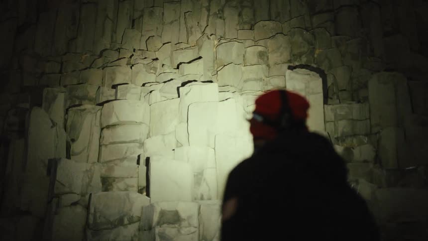 Person wearing headlamp walks through ruins