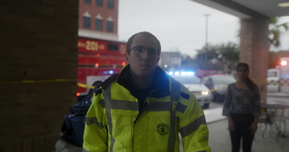 Two paramedics enter a building while rolling a large gurney