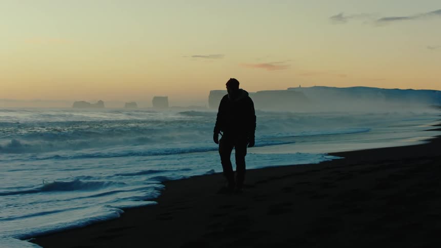 Man walking along the beach at dawn