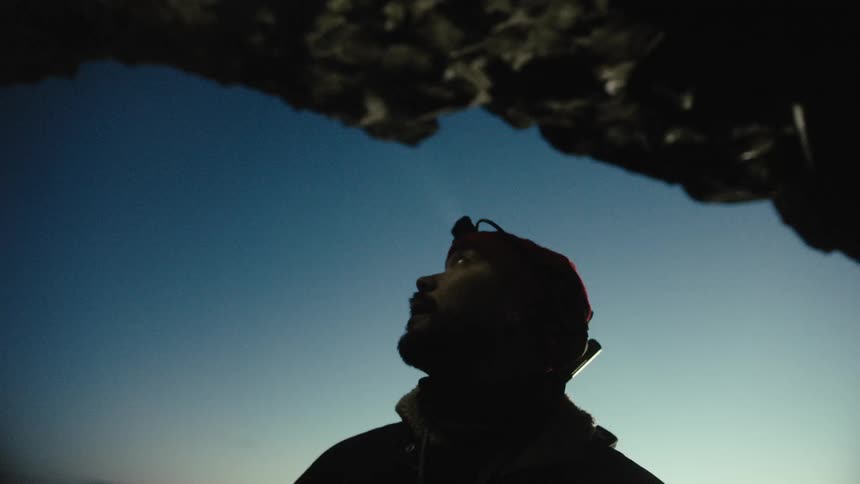 Man with a headlamp inspecting the interior of the cave