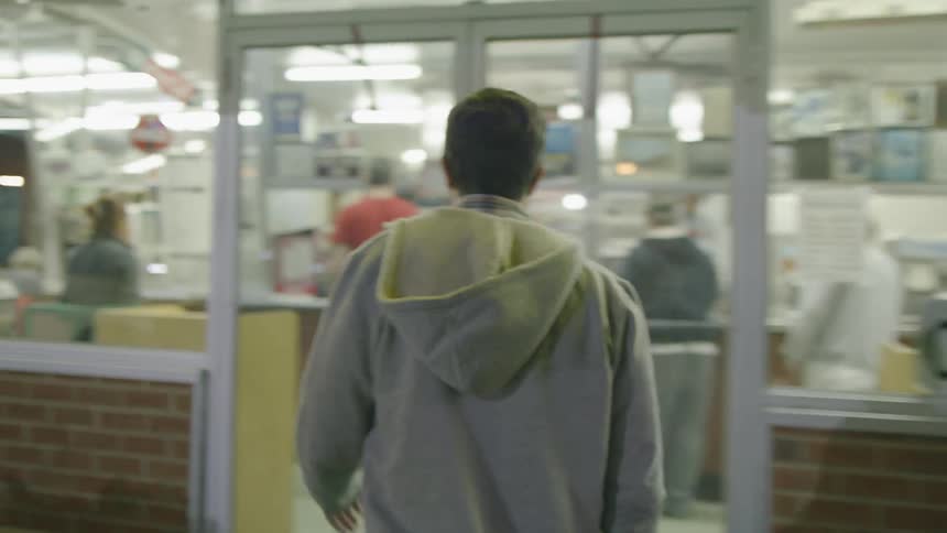 A man walks towards a shop and enters