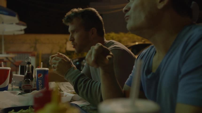 Group of people eat food at a table outside of a restaurant