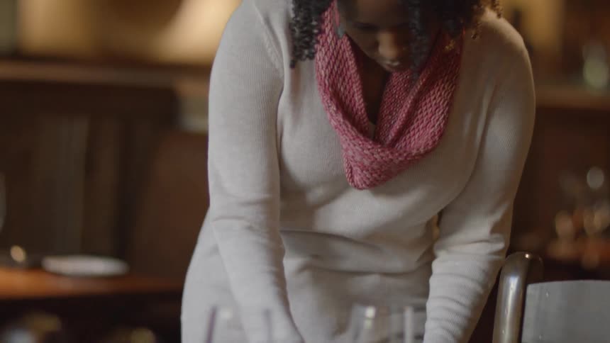 A woman is looking down setting a table