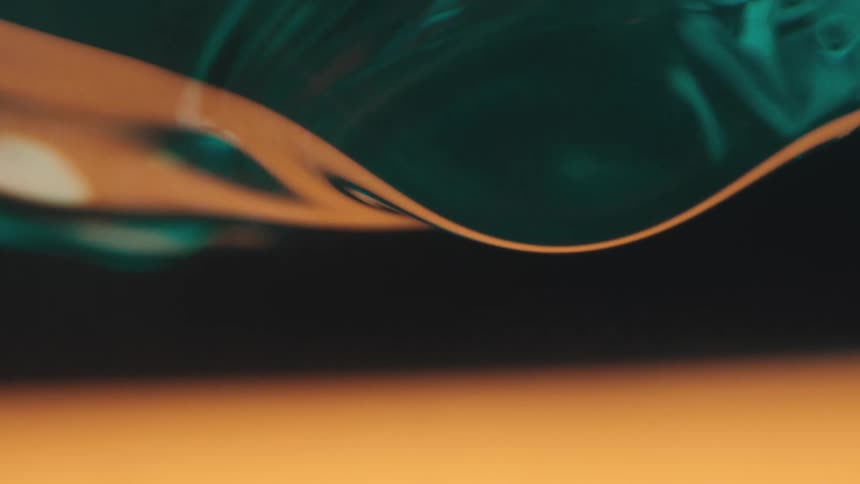 Droplets of teal and amber liquid