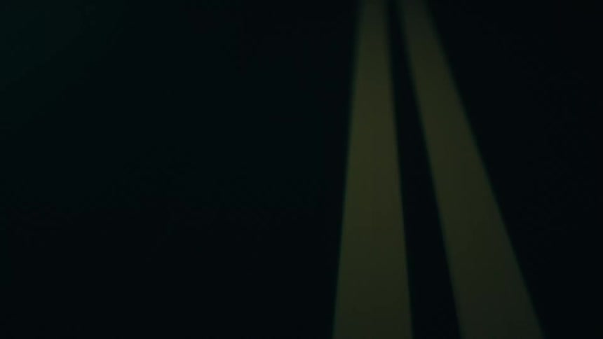 A roadway at night with yellow painted stripes down the center