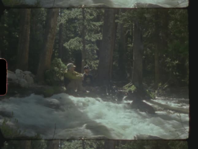 Two men sit by the stream together