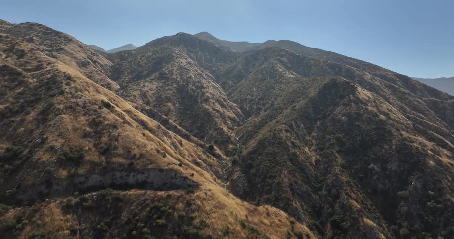 Drone view of mountain ridges with vegetation growing up the sides during the day