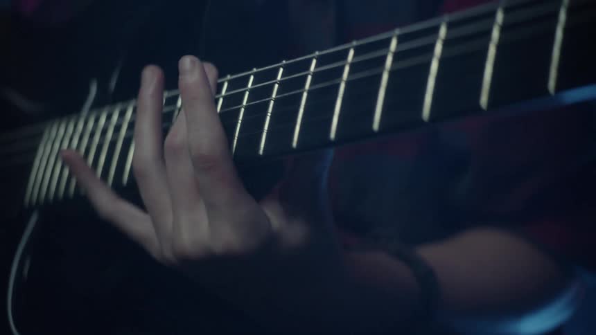 A person playing a black guitar using their fingers