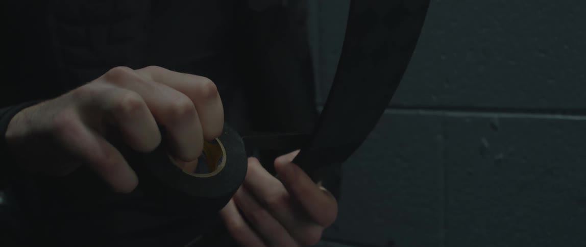 A boy is wrapping black hockey tape around a hockey stick