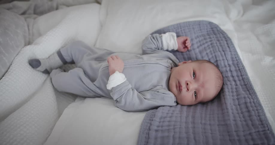 A baby lying awake in bed barely moving