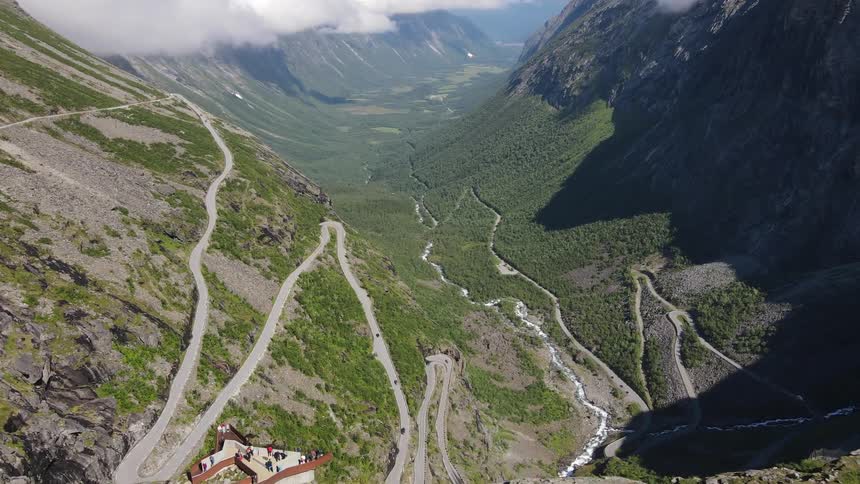View of mountains at cloud level with cliffs people hiking and vehicles moving