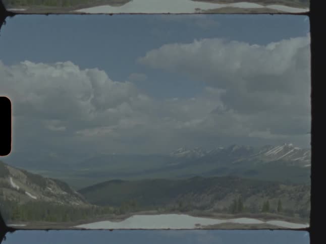 Clouds roll over a lake in the mountains caught on vintage film