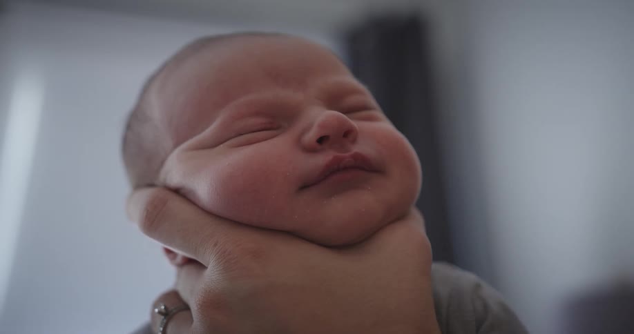 Persons hand holds babys head