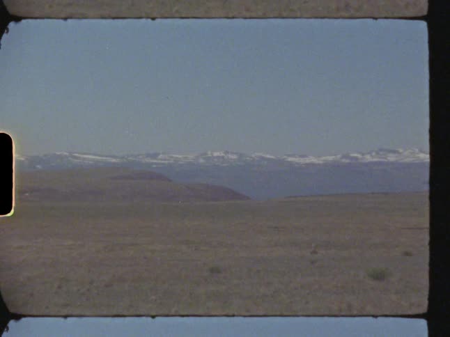 Mountains with snowy peaks on the horizon behind a desert region