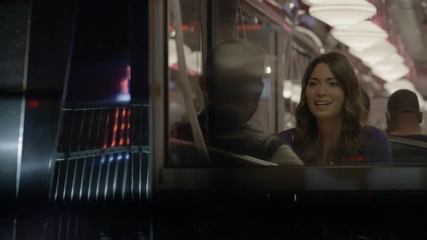 A man and woman talk inside a diner at night