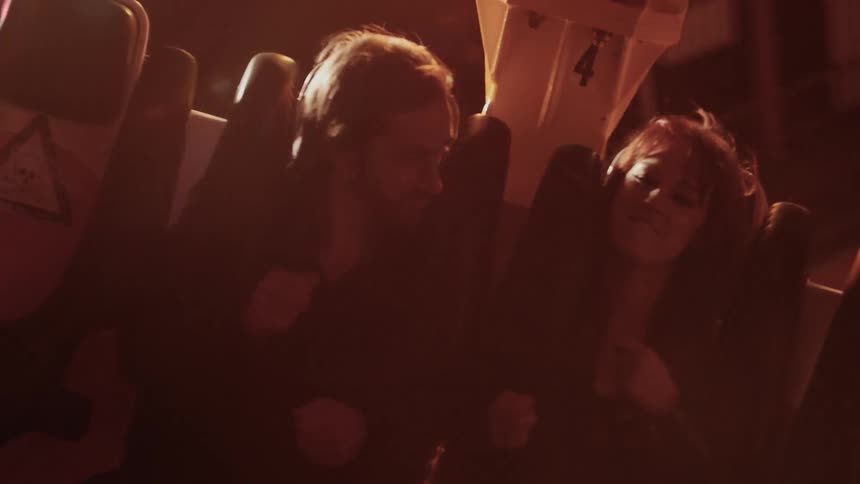 Couple riding and amusement ride at night and air drumming