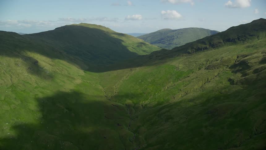 Thick grass grows along rolling hills and mountains