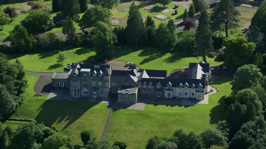 An aerial of a large estate surrounded by private manicured grounds in the summer