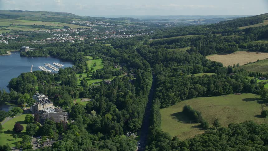 Aerial of a rural neighborhood near water with a main road traveling through it with trees on either side