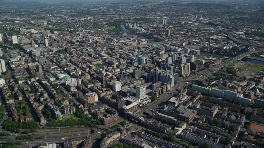 Aerial of a city with buildings built close together on a bright sunny day with a highway traveling through it