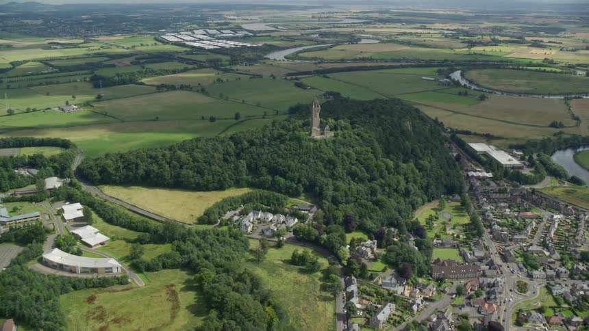 Drone view of a rural area with flat grass lands and a small village with an architectural structure in a forest of tree