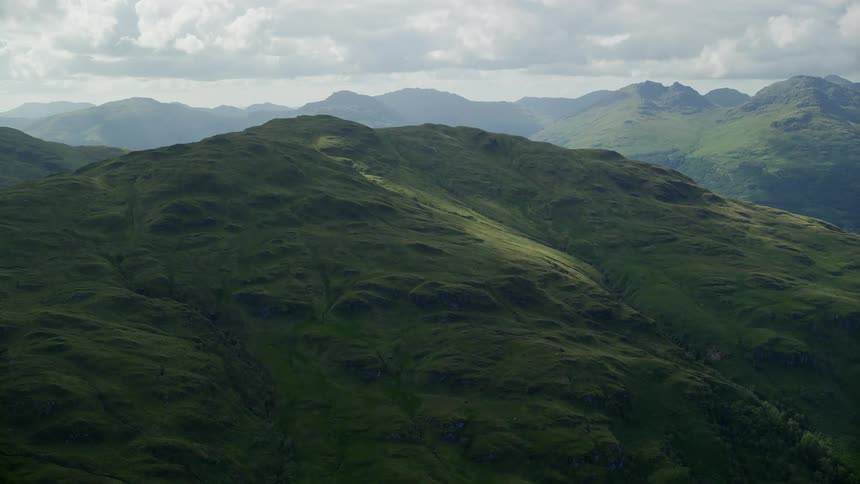 Green grass coats the surface of a sloping mountain side