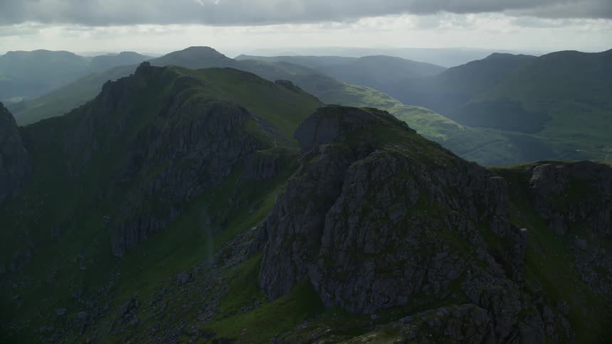 A layer of grass coats the surface of towering rocky mountain range