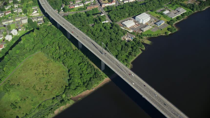 Aerial view of a suspension bridge over a river next to the suburbs