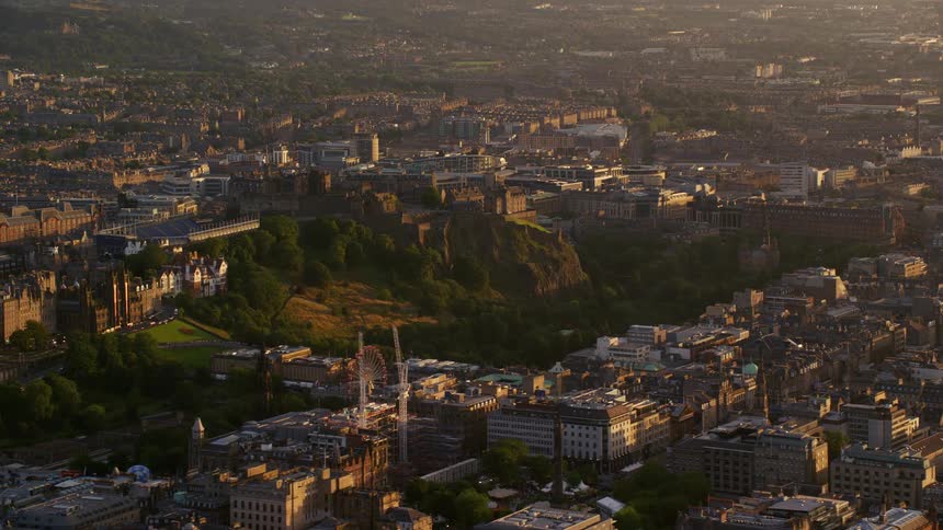 Drone view of a city built around a small mountain with architectural buildings built near it on a sunny day