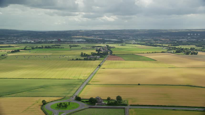 A huge highway that passes through fields of grass and agriculture in a rural region