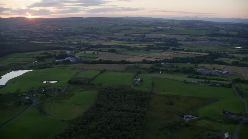 A rural region with small houses and several fields of grass