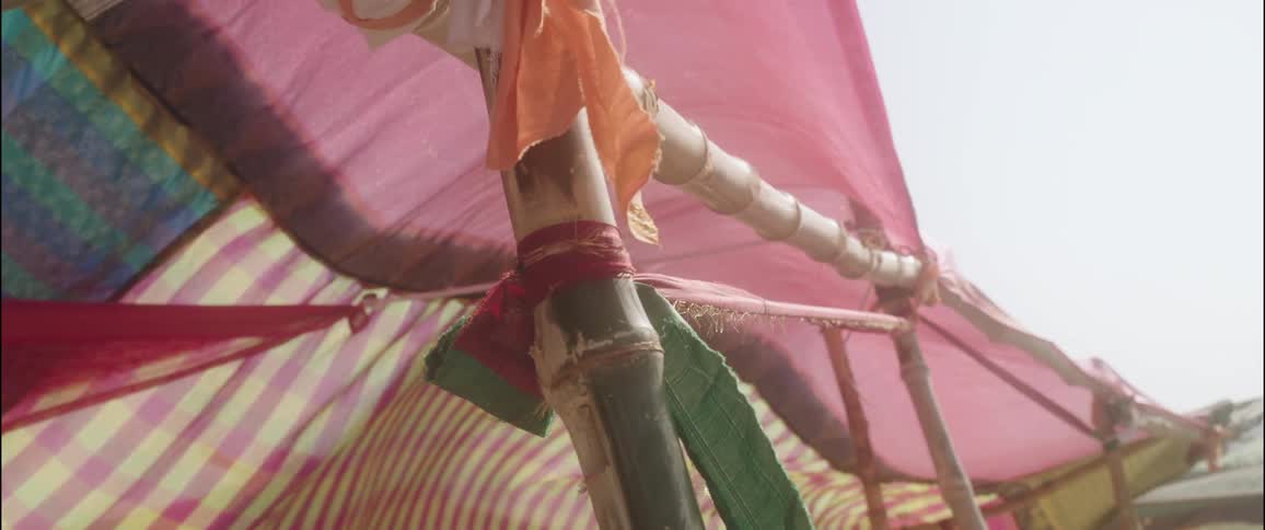 A bamboo scaffold has colorful pieces of fabric hanging from it