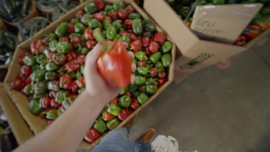 A first person perspective of a man shopping for produce at farmers market