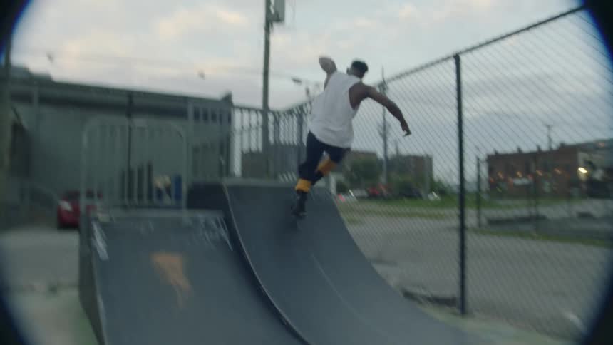 A man doing tricks on a skate ramp using roller skates