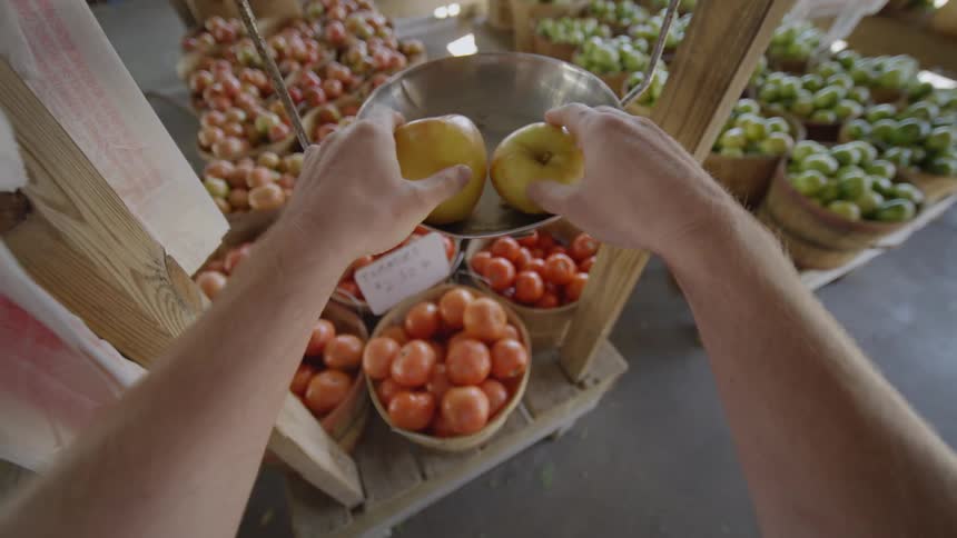Human girls picking apples at a market and weighing them and putting them in a bag