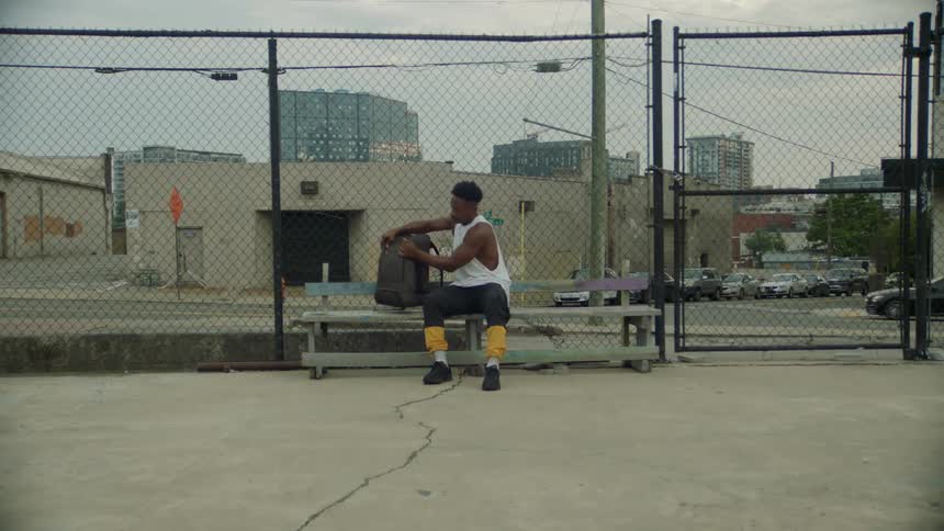 Young man ready to workout sits on a bench to unpack his backpack