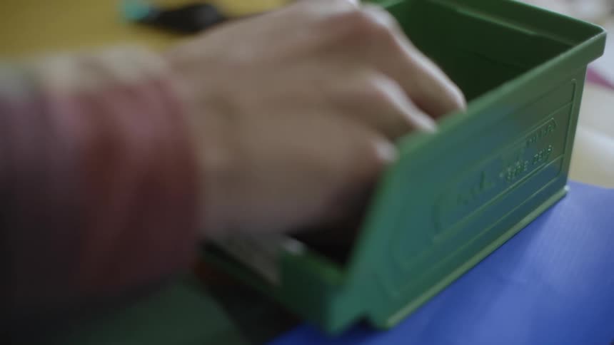 A persons hand picking up a zipper from a jar