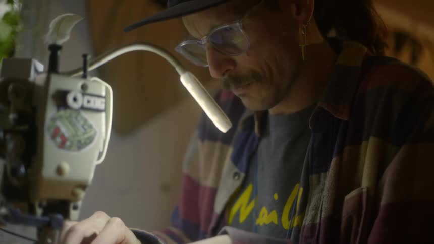 Man sitting and working with a sewing machine in an indoor environment