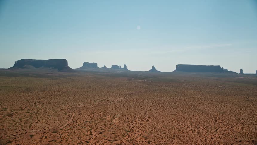 Dirt roads wind through scrubland to plateau and mesa terrain