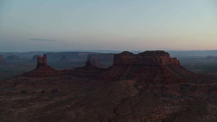 Scrub covers land between plateaus under a red tinted sky on a hazy day