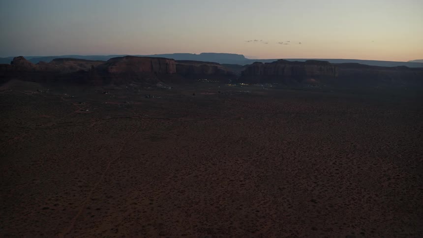 Aerial view of a settlement at the base of a mesa in the badlands at evening