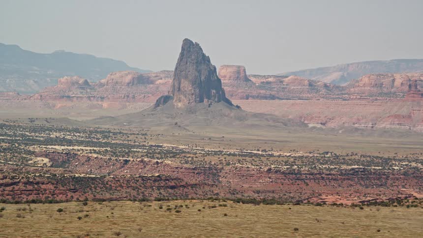A prominent jagged rock formation stands out amidst the desert landscape
